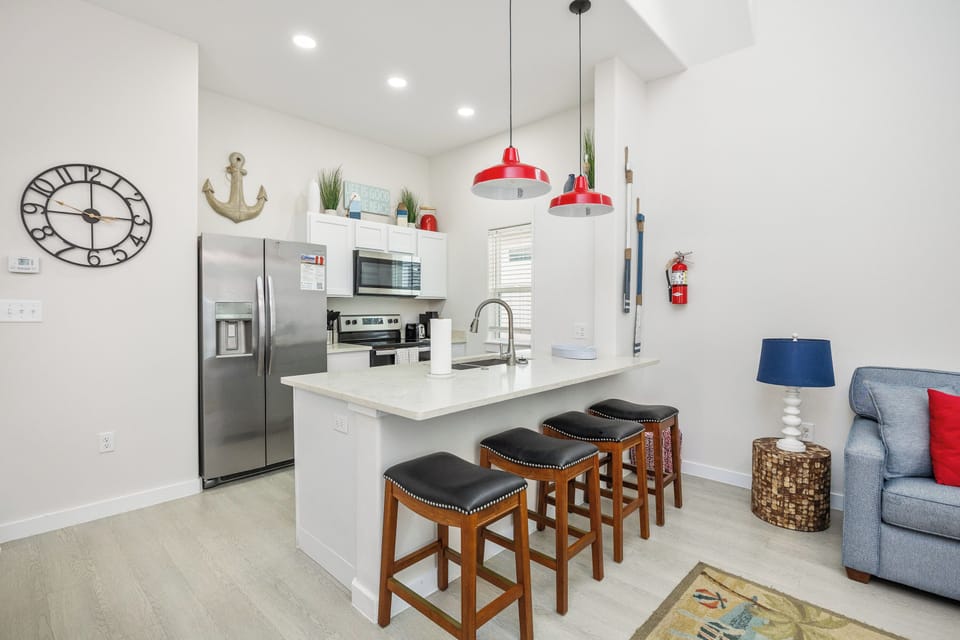 Your modern kitchen features stainless steel appliances, coastal décor, and breakfast bar seating—perfect for morning coffee together.