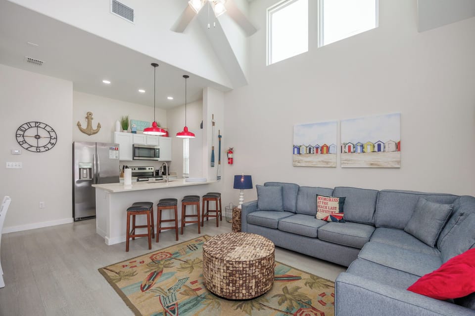 Relax in your bright open-concept living space with soaring ceilings, cozy sectional seating, and a fully equipped kitchen perfect for home-cooked meals.