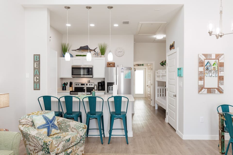 Enjoy your morning coffee at this bright kitchen island while the coastal decor and turquoise accents create a relaxing beach house atmosphere.