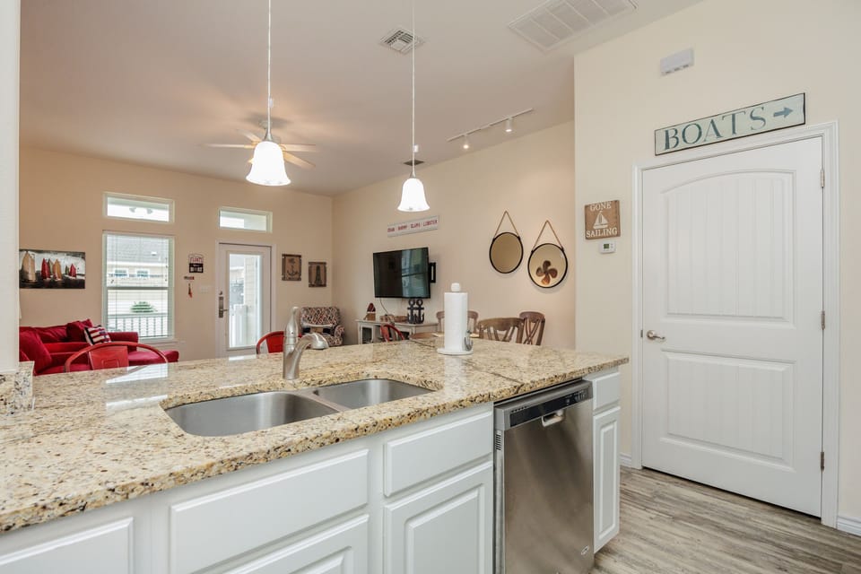 Your fully equipped kitchen features granite counters and stainless appliances, flowing seamlessly into the nautical-themed living space.