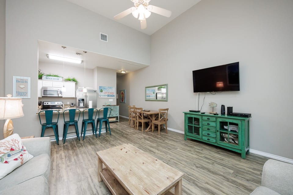 Unwind in your bright, open-plan living space featuring turquoise bar seating, coastal decor, and modern amenities for memorable vacation moments.