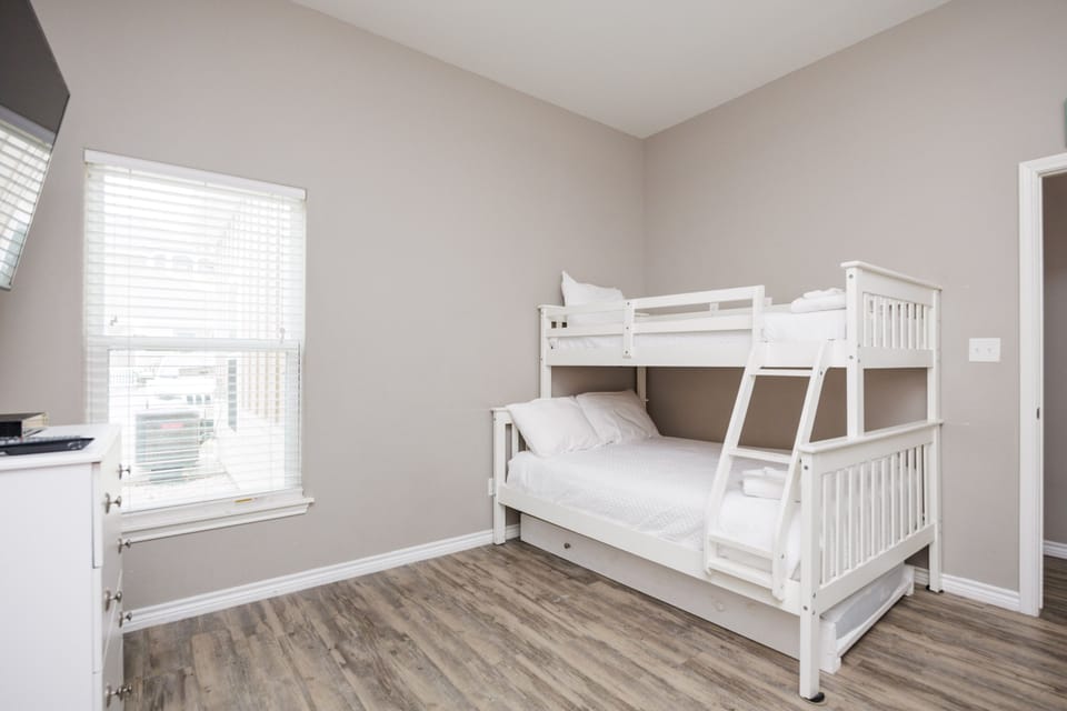 Your kids will love sharing this bright bedroom with sturdy white bunk beds and plenty of natural light streaming through the windows.