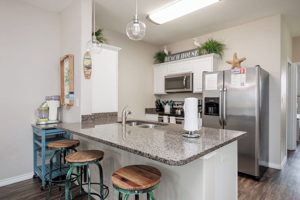 Your beach-themed kitchen features granite counters, stainless appliances, and a breakfast bar perfect for morning coffee or casual meals.