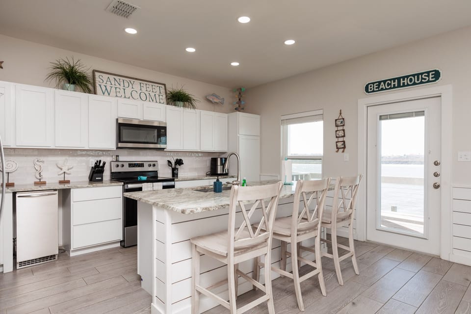 Your bright, coastal-themed kitchen awaits with a granite island for morning coffee and beach views through glass doors.