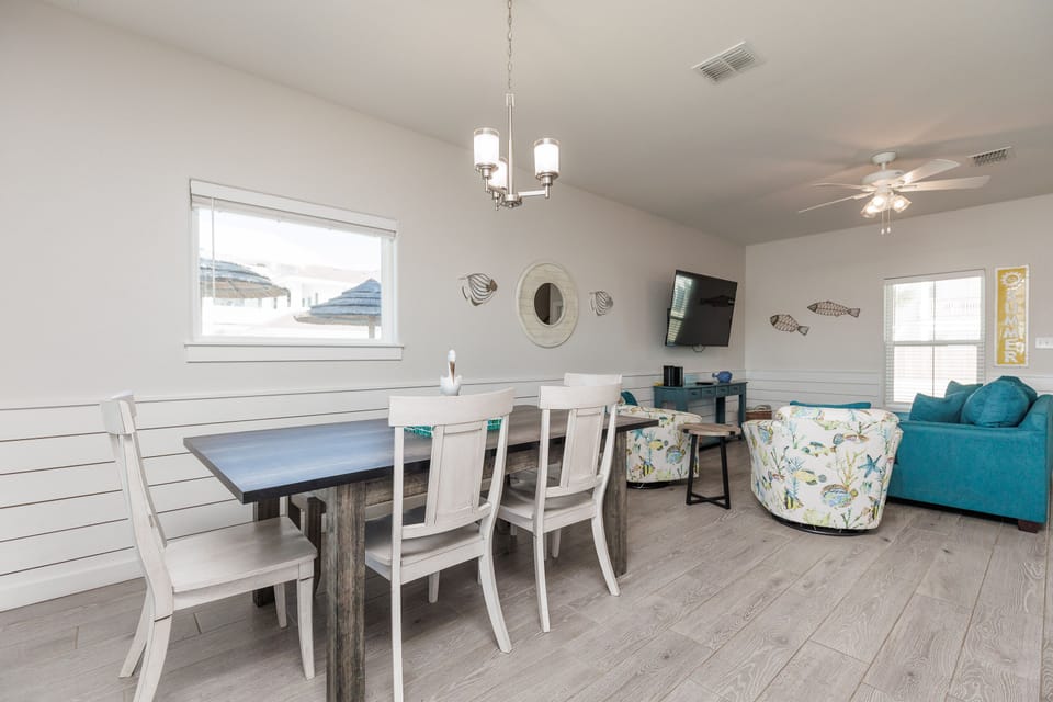 Relax in this bright, coastal-themed living space where you can gather around the dining table or unwind on comfy seating.