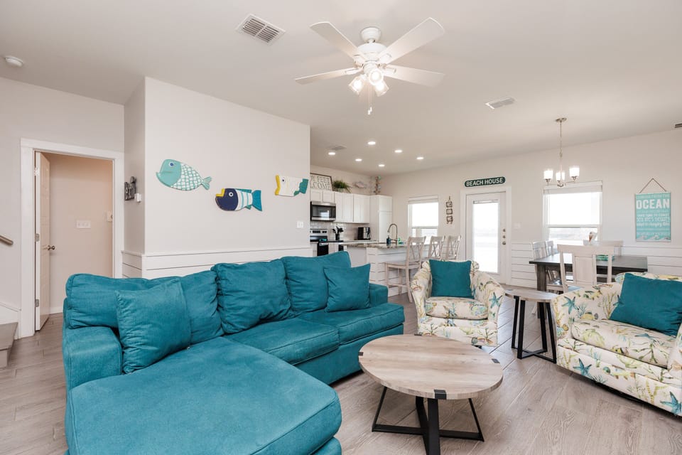 Relax in your bright, coastal-inspired living space featuring a plush turquoise sectional and cheerful beach decor that instantly makes you feel at home.