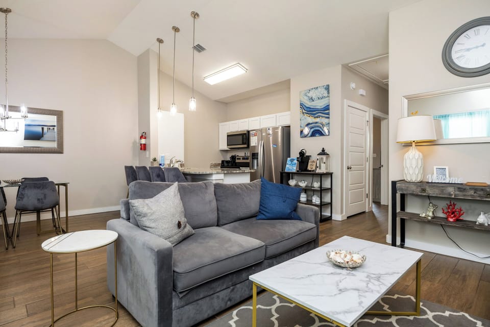 Sink into plush grey seating while admiring the open layout connecting your living space to a fully-equipped kitchen with stainless steel appliances.