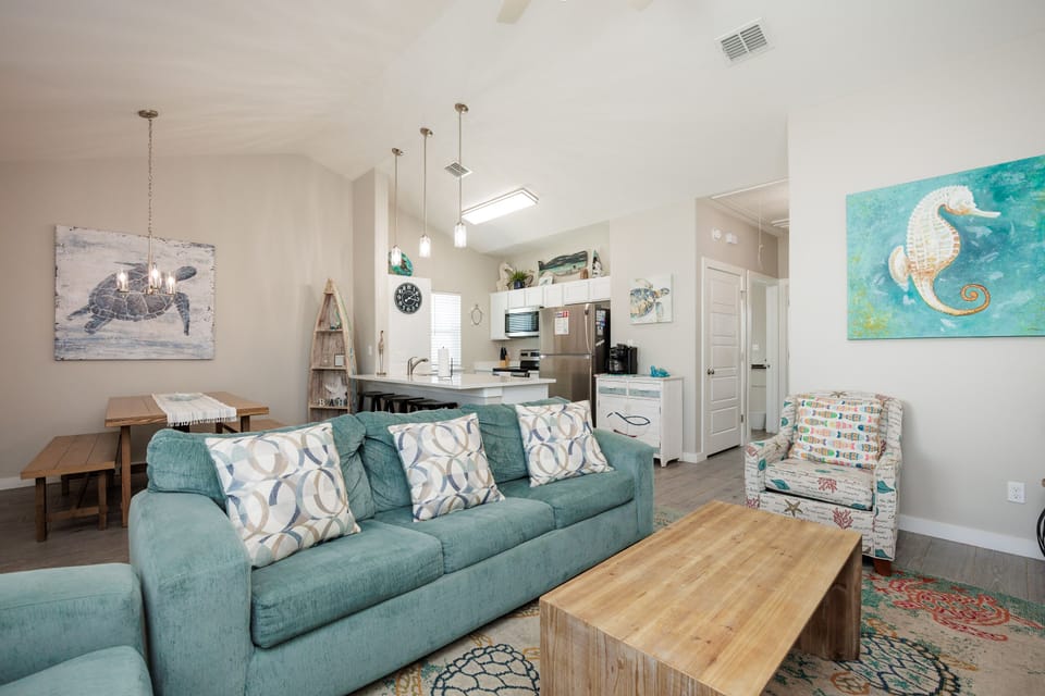 Unwind in your coastal-themed living space where turquoise accents and seahorse art create a beachy atmosphere for relaxing.