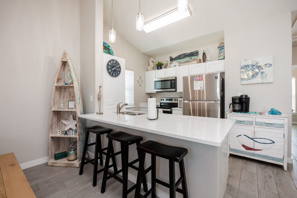 Gather around this bright coastal kitchen island for morning coffee or casual meals, with ocean-themed touches creating a relaxing beachside atmosphere.