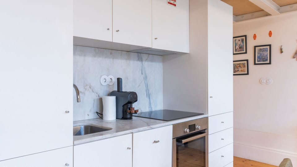A compact yet functional kitchenette equipped with essential appliances like a fridge, oven, stovetop and coffee maker #modern #practical