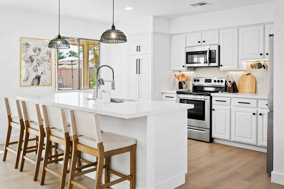 Fully-stocked kitchen with stainless steel appliances and island with barstool seating for four