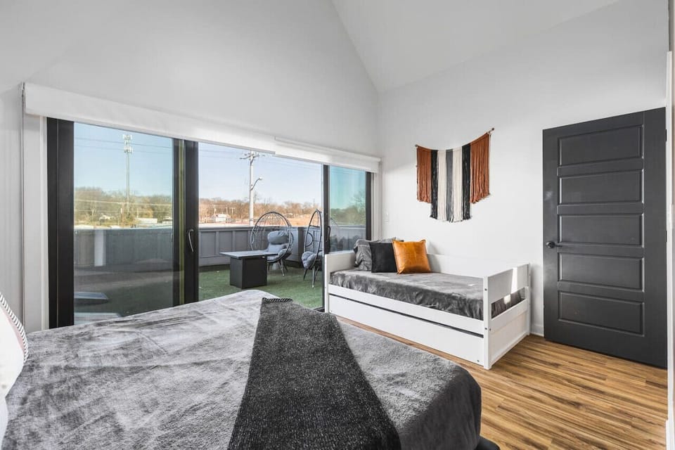 Upstairs bedroom #3 with a King bed, twin + trundle bed, and large sunny patio space with outdoor furniture & cornhole.