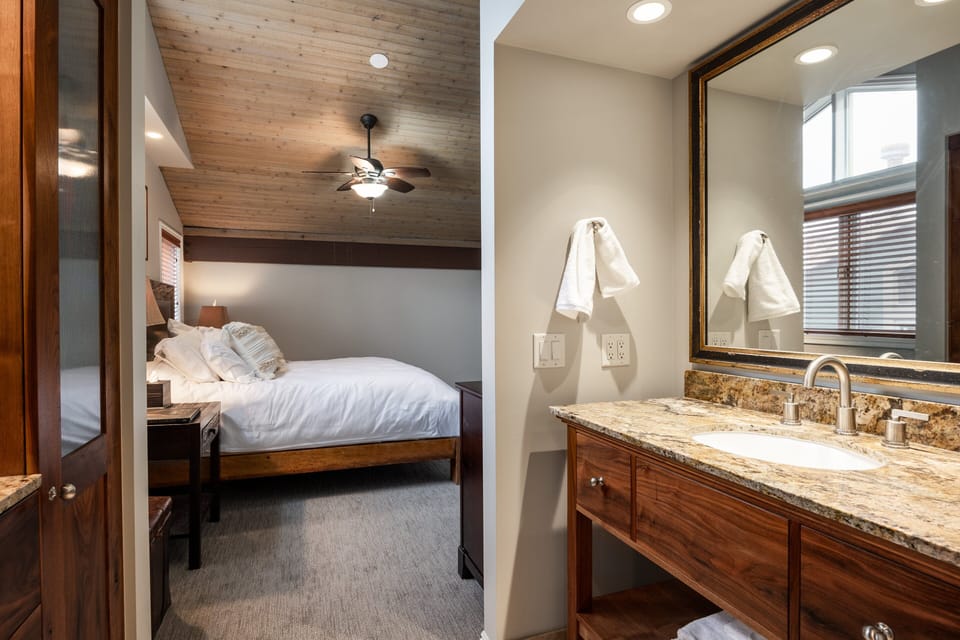 - Step from your rustic retreat into a private ensuite with warm wood finishes
- Granite countertops, oversized mirror, and under sink storage add both style and function
- Thoughtful lighting and natural textures create a spa like start to your day