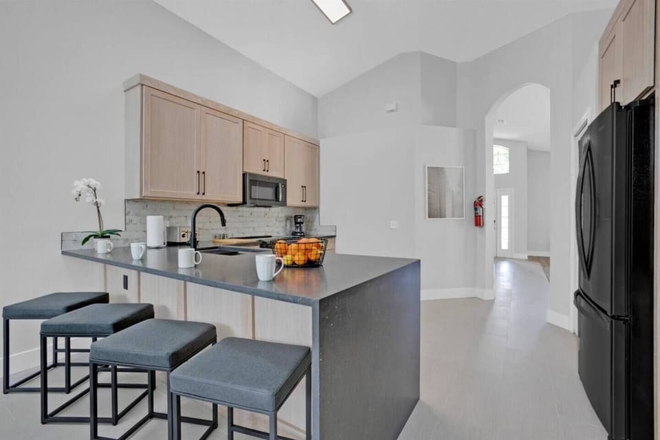 The kitchen has bar table with 4 bar stools