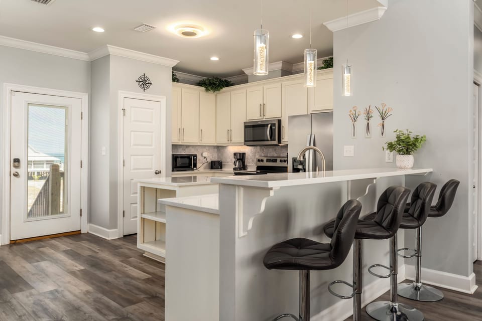 Your fully equipped kitchen features sleek white cabinets, stainless steel appliances, and a breakfast bar perfect for morning coffee or quick meals.