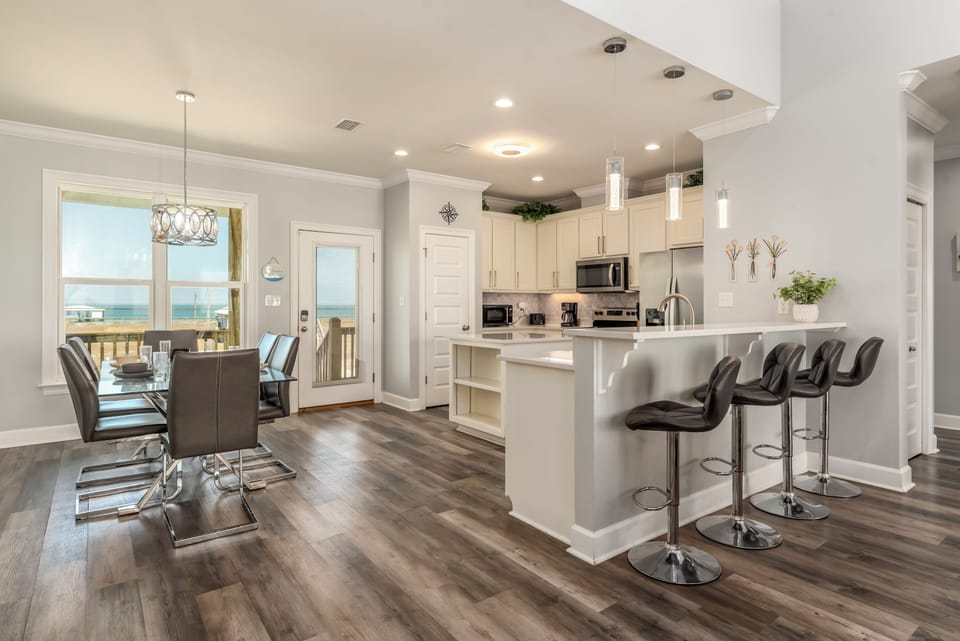 Your modern kitchen flows seamlessly into the dining area, where ocean views through the windows create the perfect backdrop for memorable meals.