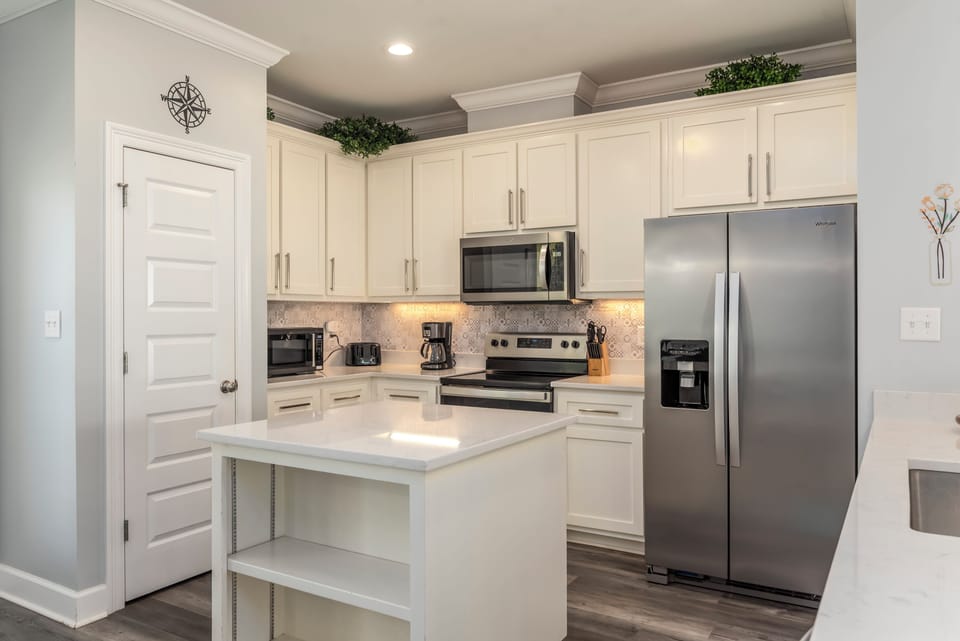 Step into your fully equipped kitchen where white cabinets and stainless appliances create the perfect space for cooking your favorite meals.