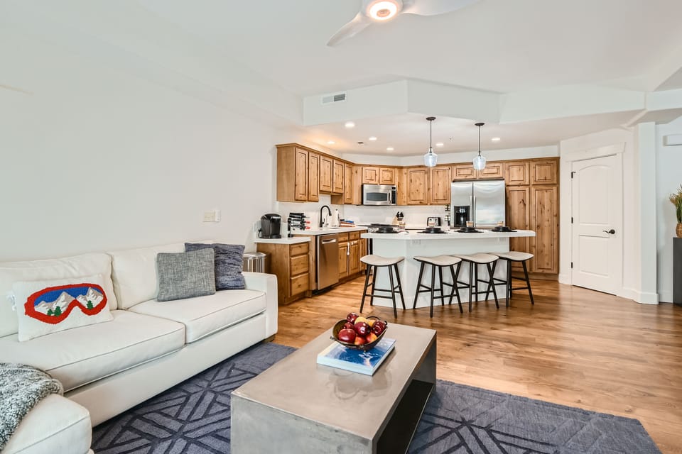 Bright, open-concept living space with comfortable seating and a modern kitchen. Perfect for relaxing or entertaining, featuring hardwood floors, cozy décor, and easy access to Park City dining, skiing, and year-round mountain adventures.