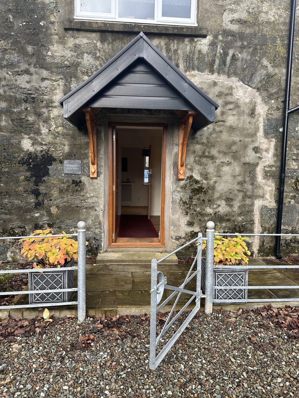 Entrance to  Cottage with lawned garden with furniture on the right.
