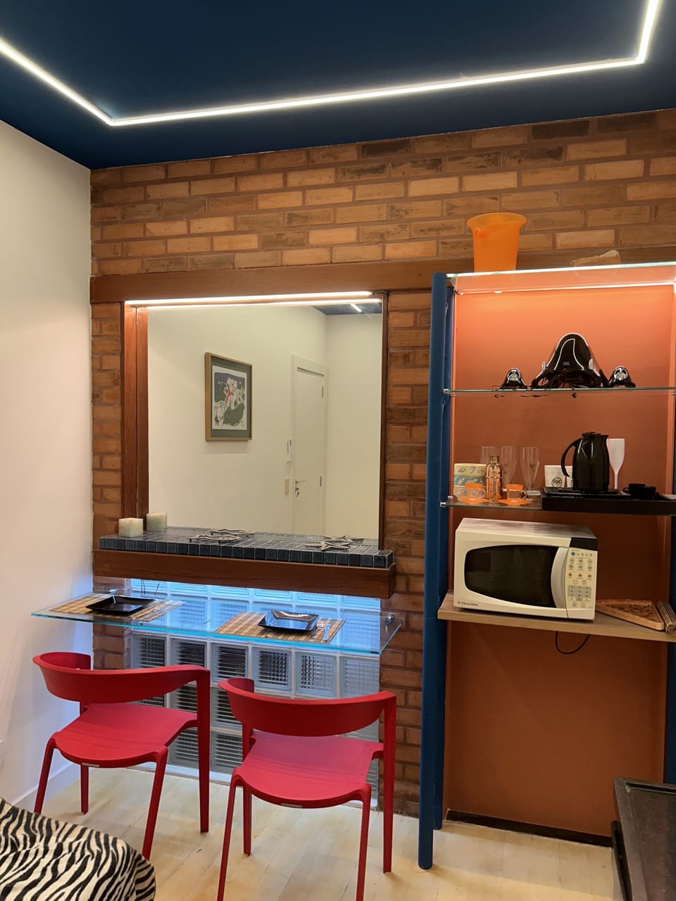 sala de estar com soft kitchen e bancada de vidro para refeições