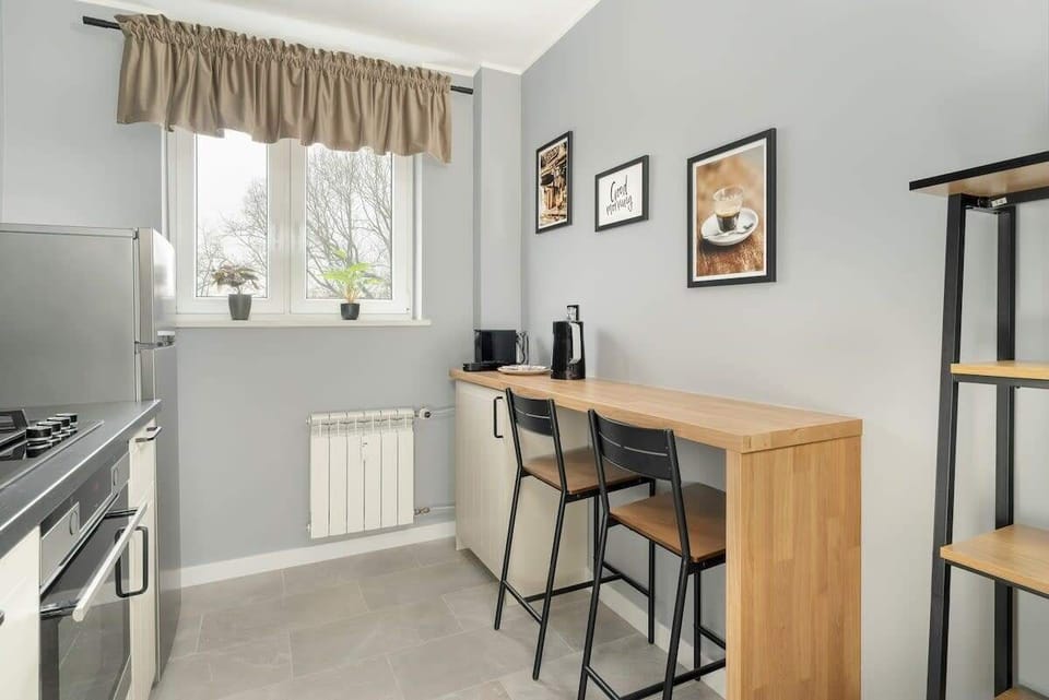 A cozy breakfast nook with a wooden bar table, high stools, and decorative wall art, creating a charming and functional dining area.
