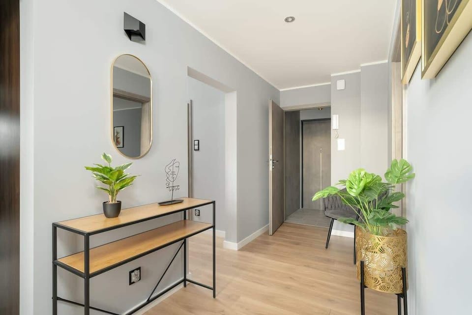 An elegant hallway with a stylish console table, decorative plants, and minimalist decor, maintaining a bright and welcoming ambiance.
