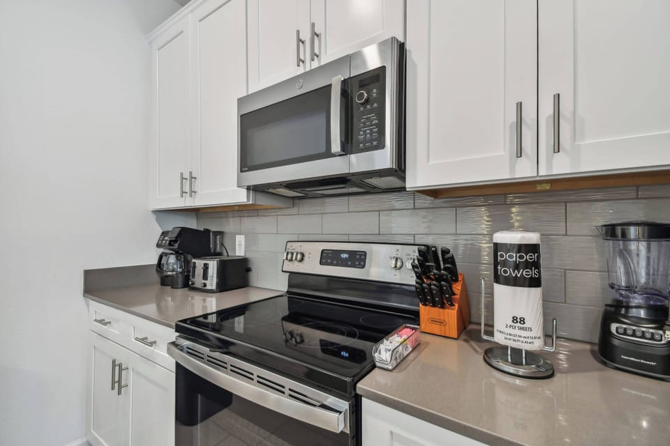Discover culinary delights in this stylish kitchen with sleek stainless steel appliances and bright white cabinetry, creating an airy atmosphere. The spacious quartz countertops invite you to prepare your favorite meals with ease.