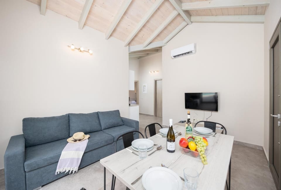 Open-plan living room with sofa, dining area, kitchen, A/C, WiFi internet, and satellite TV