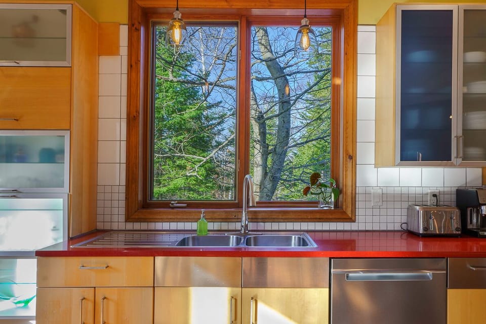 Coin cuisine avec grande fenêtre donnant sur la forêt — un cadre naturel inspirant.