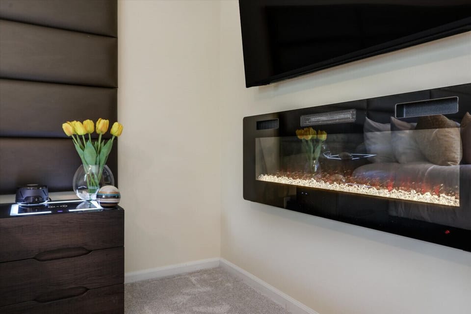 Embrace the inviting warmth of this bedroom, where the crackling fireplace illuminates the space with a comforting glow, offering solace and relaxation during colder nights.