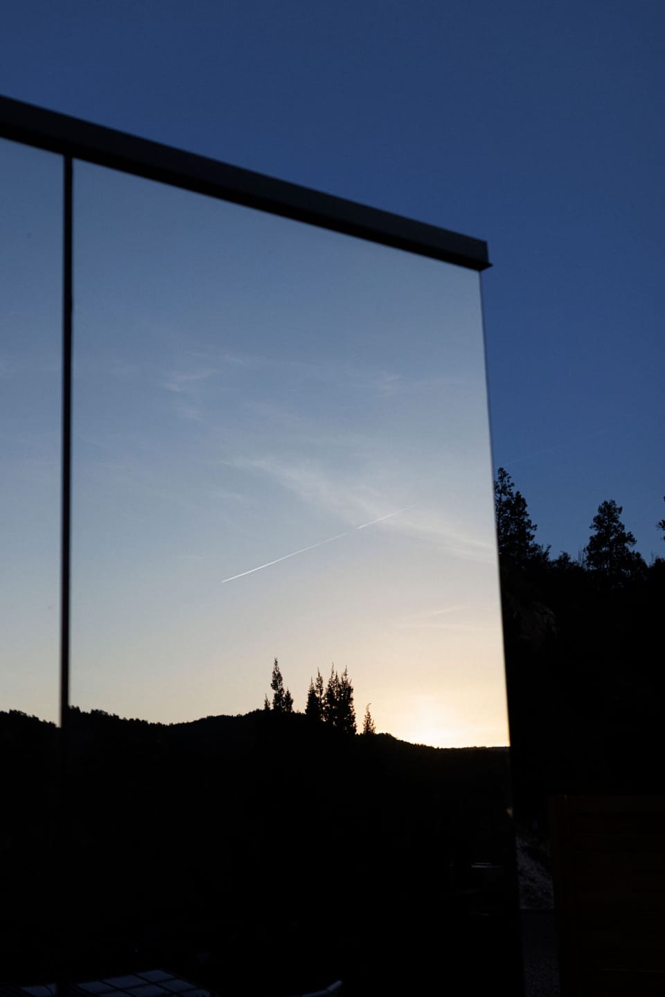 Mirror House exterior at dusk, designed to reflect the surrounding cliffs, trees, and Southern Utah sky.