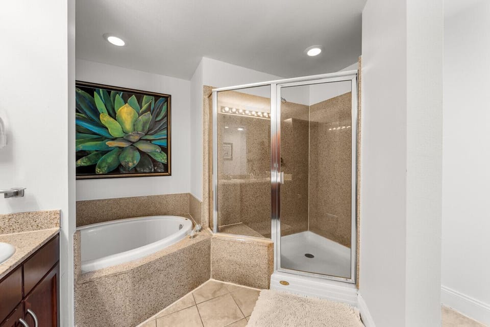 Spacious master bathroom featuring a soaking tub, a separate glass-enclosed shower, and granite accents for a relaxing retreat.