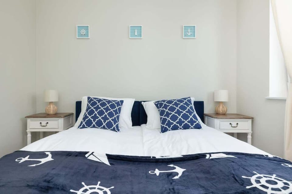 A nautical-themed bedroom with anchor-patterned bedding and a minimalist, calming decor.






