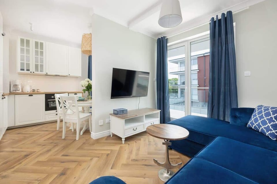 A view of the dining and living space, featuring a white table, blue decor, and natural light.

