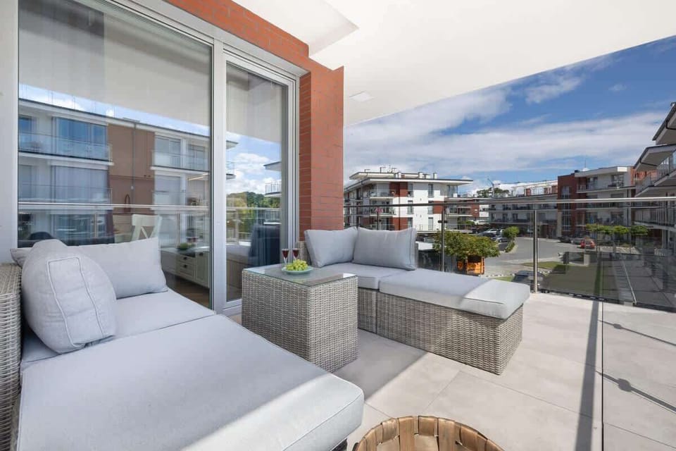A spacious balcony with stylish wicker furniture, plush cushions, and a serene view of the surrounding area.
