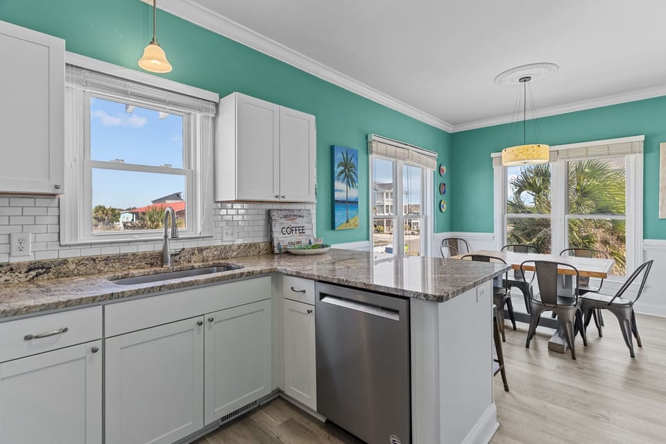 Oak Island, NC kitchen with teal walls, white cabinets, granite island, stove, microwave, sink, stools, coffee décor, subway tile, and beachy style.