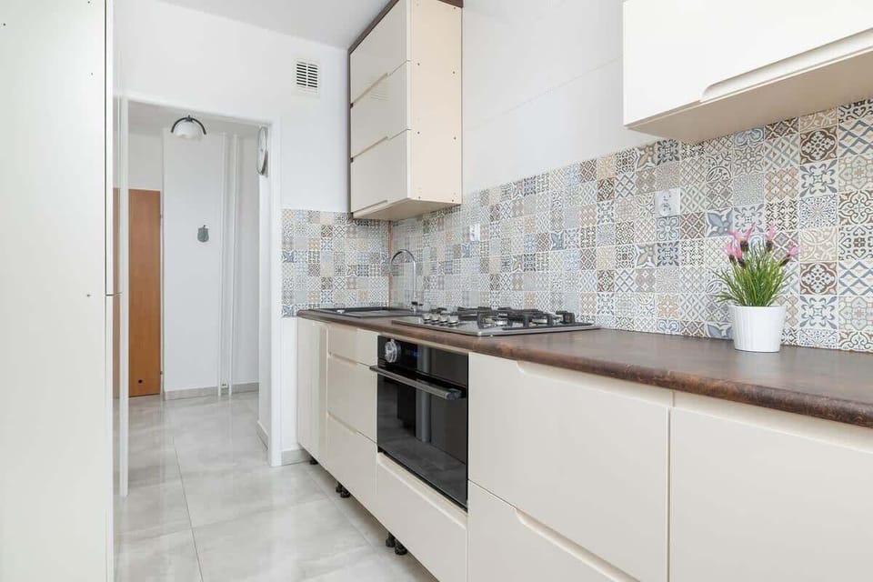 Another angle of the kitchen showcasing a gas stove, white cabinetry, and a minimalist layout, enhancing the cooking space.
