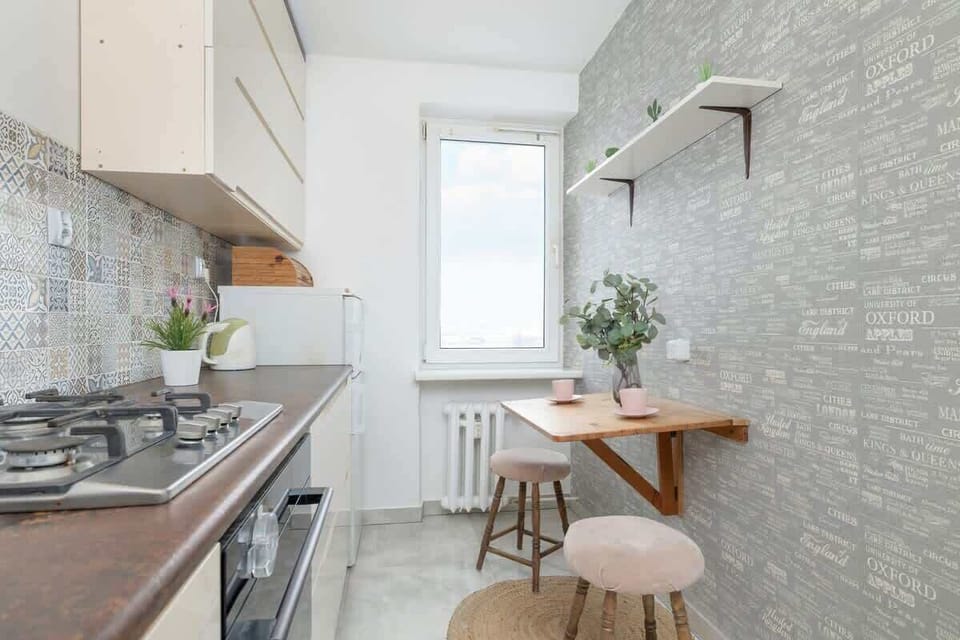 A modern kitchen with a mosaic tile backsplash, white cabinets, and a wooden breakfast bar, maintaining a stylish and functional cooking area.
