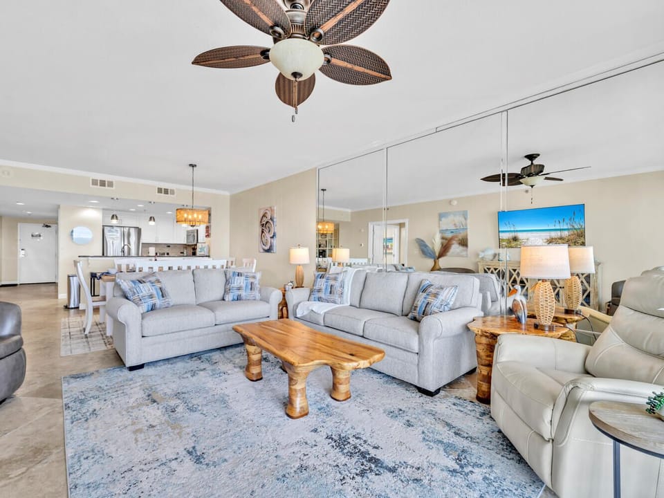 Relax in your spacious coastal living room with plush sectional seating, warm wood accents, and beachy decor that invites you to unwind in comfort.