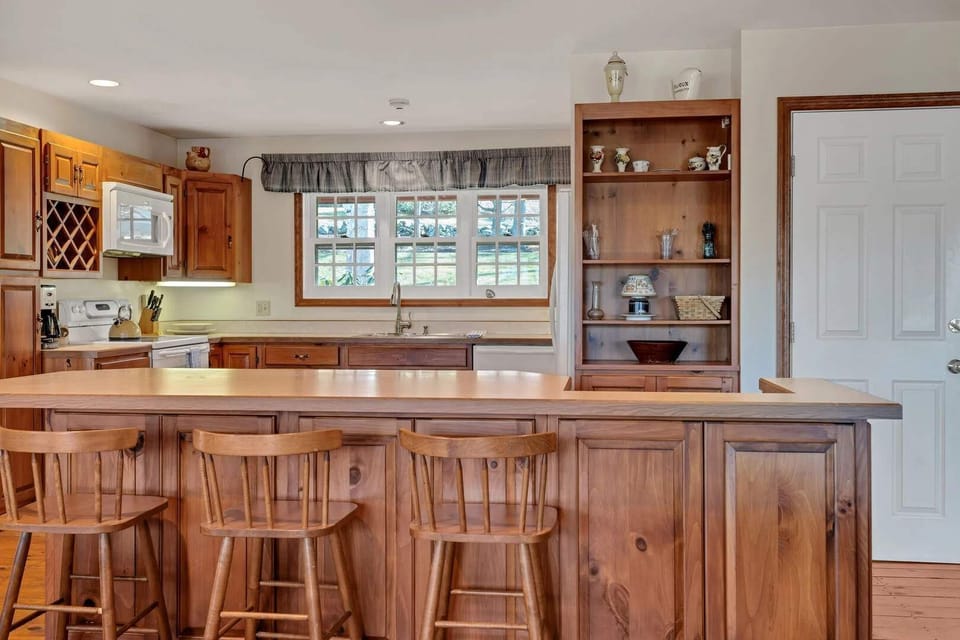 Dining room and kitchen with breakfast bar seating and pine hutch