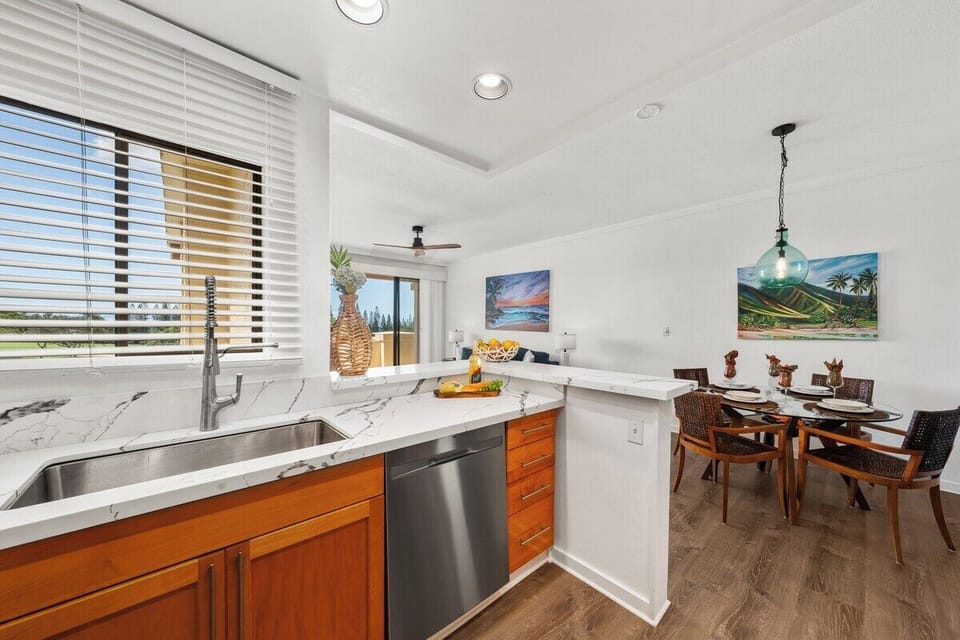 Open kitchen with marble counters flowing into a tropical dining nook.