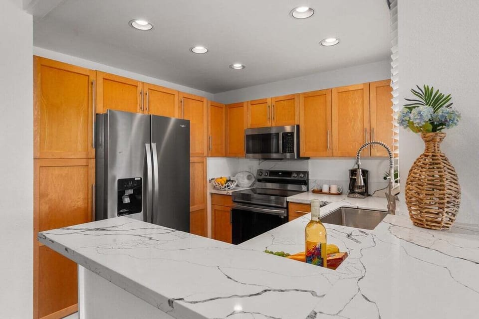 Cook in a modern kitchen with stainless steel appliances and marble counters.