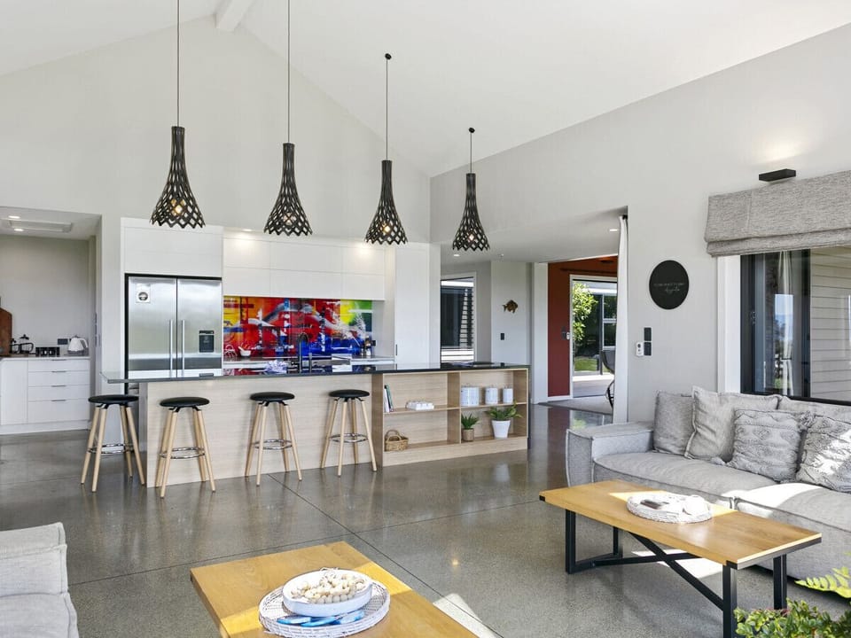A generously designed open-plan kitchen, elegantly equipped with an oven, fridge/freezer, dishwasher, and a complete set of kitchen utensils and cutlery.