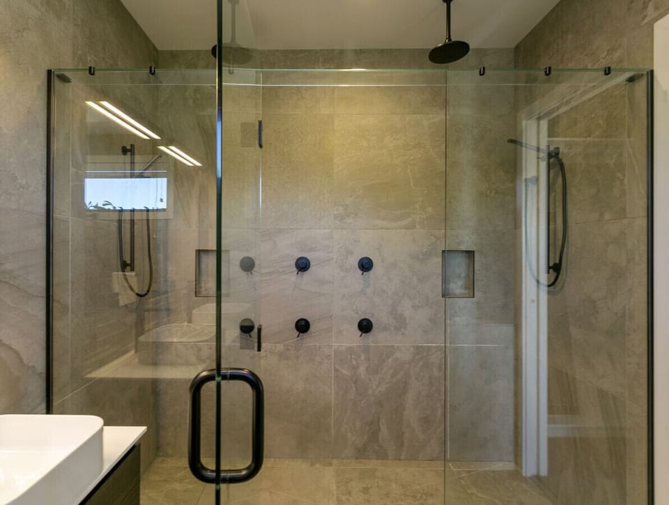 Elegant master bathroom boasting a dual vanity and a lavish double shower offering a choice of soothing waterfall or rain showerheads.