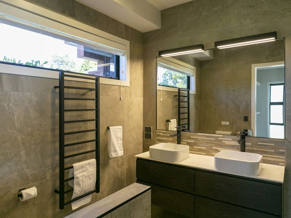 Elegant master bathroom boasting a dual vanity and a lavish double shower offering a choice of soothing waterfall or rain showerheads.