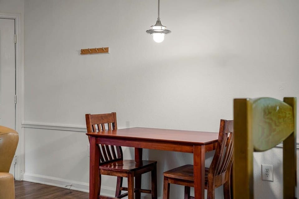 Cozy dining area with a wooden table and chairs under a hanging light.