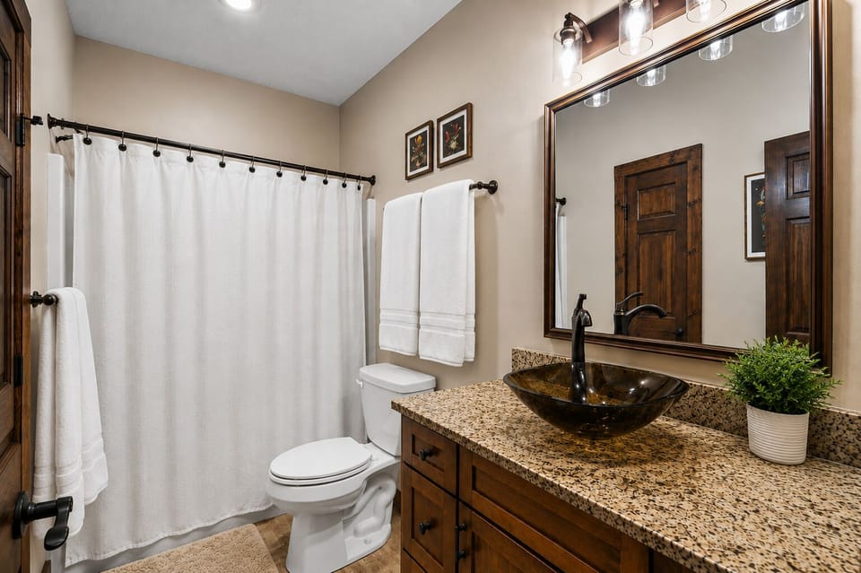 Bath #2 with granite countertop, glass vessel sink, and bath/shower combo (located in hall by master bedroom #2)