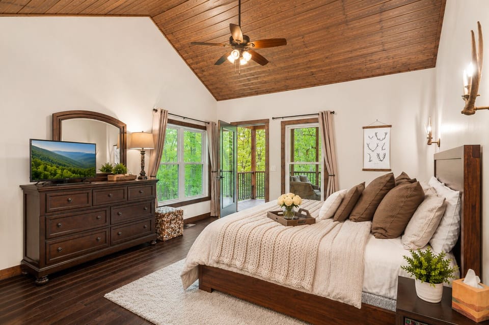 Master bedroom w/ king bed, vaulted wood ceiling, smart TV, and door to screened in porch