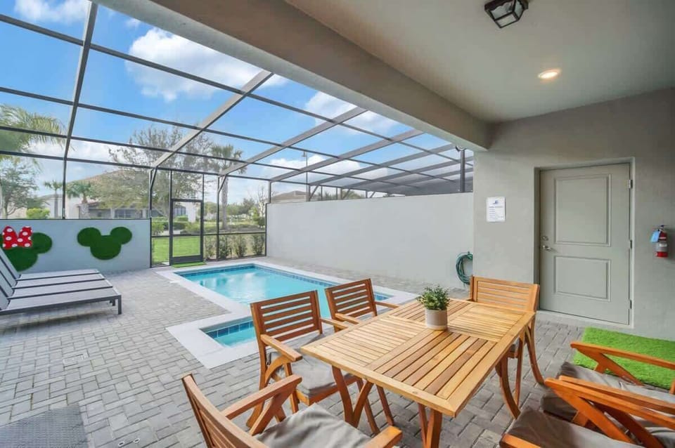 Covered patio with wooden dining set overlooking a screened pool area.
