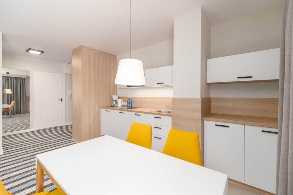 Another angle of the dining and kitchen space, showcasing modern white cabinetry and sleek wooden accents.
